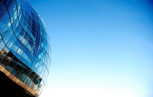 A view of the exterior of The Glasshouse taken from a low angle with a bright blue sky in the background.