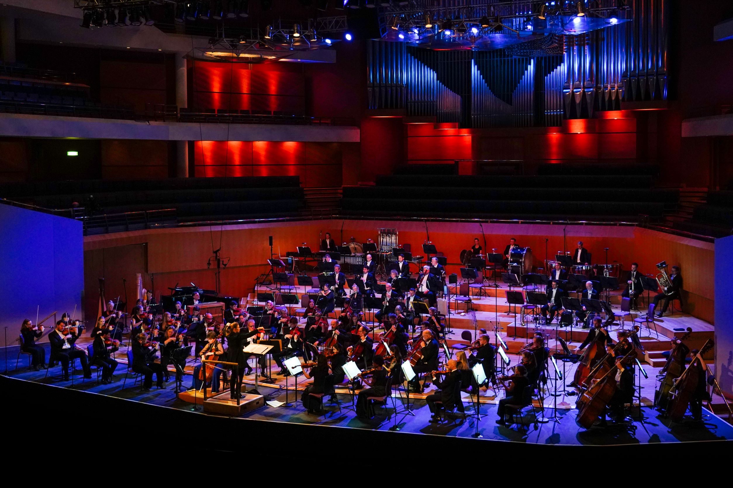 a large orchestra on a stage with red and blue lights
