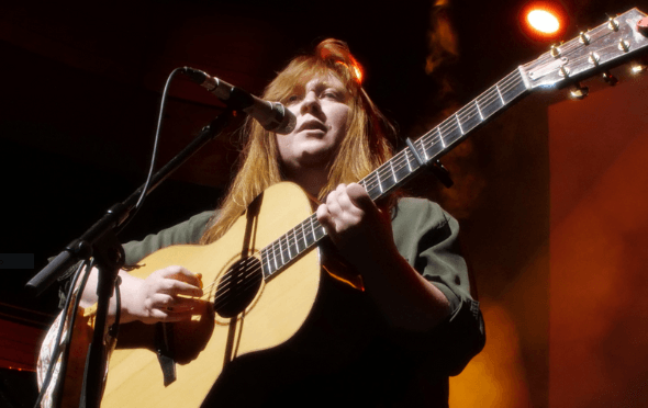 Holly Clarke playing a guitar on stage