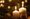 two lit candles, two pinecones and some green fir tree branches