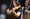 Emma Fisk a woman with long black hair smiling while playing a violin. There is also a man in the background playing a double bass.