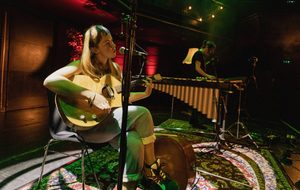 a person sitting with a guitar under red lighting