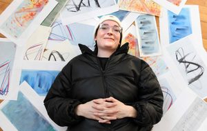 a person in a black coat and white hat laying on art