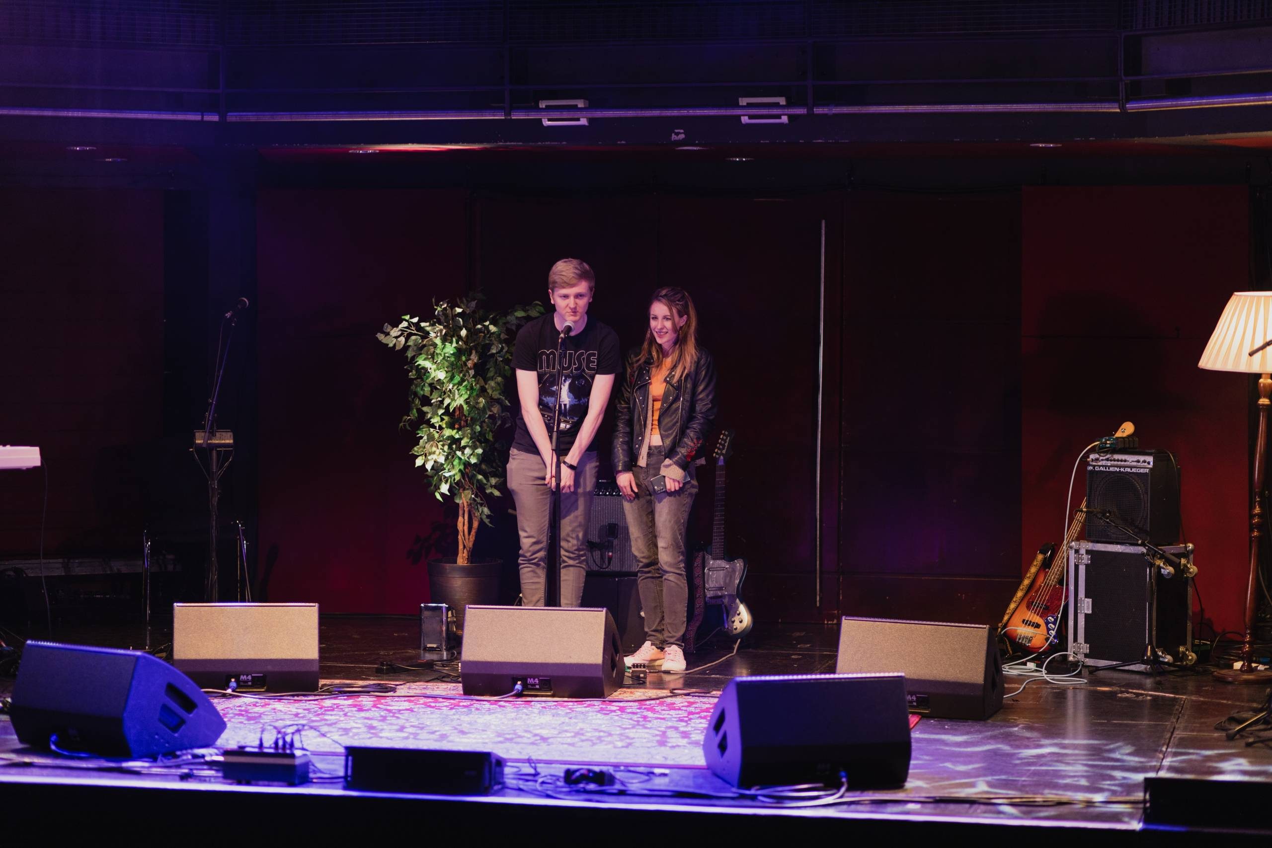 two people standing on a stage under purple lights