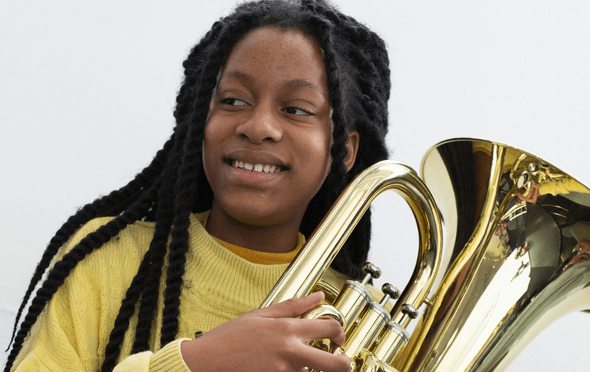 young musician in a yellow top holding a Trombone