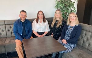 four people sitting around a brown table