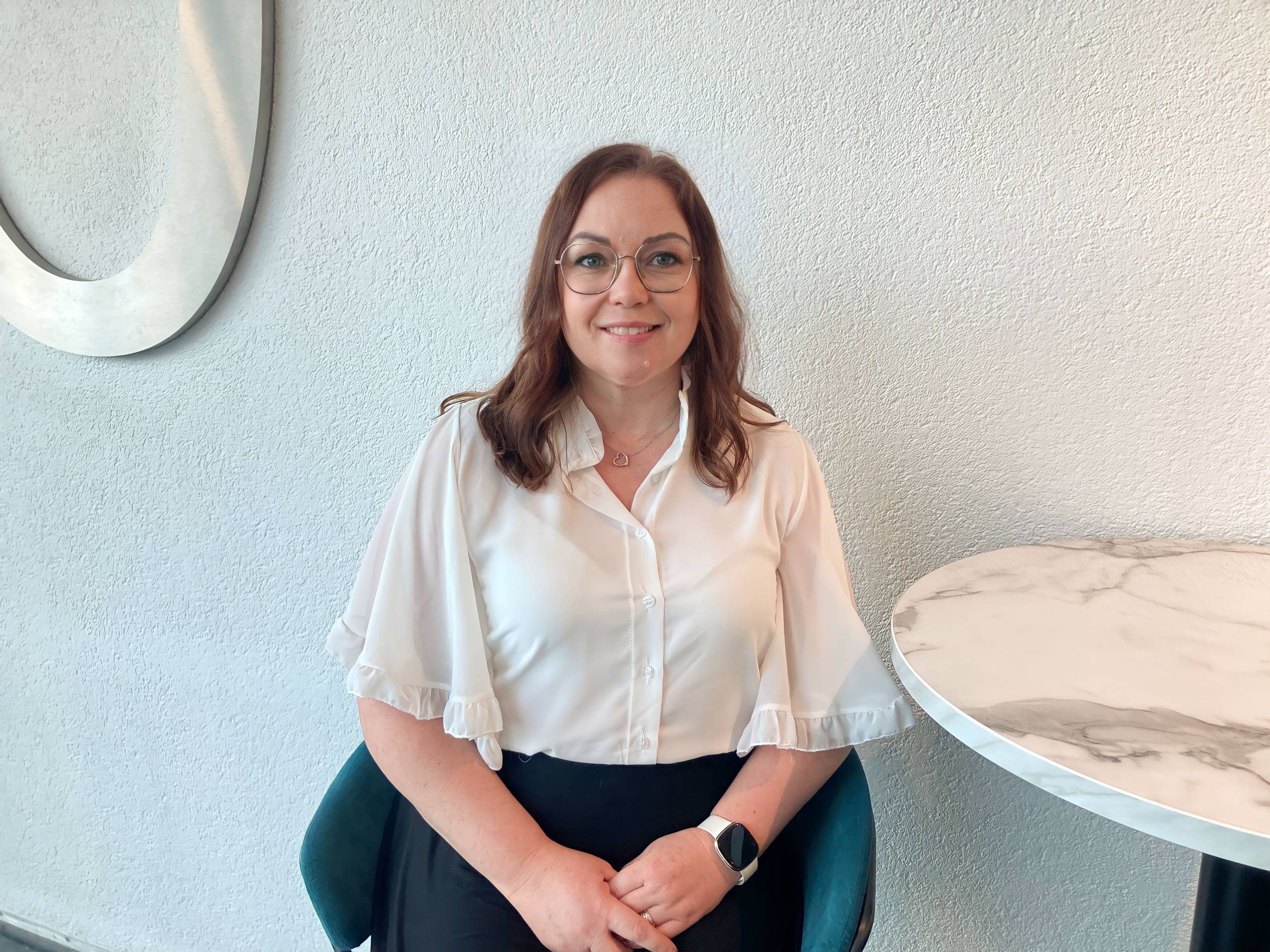 Person with glasses and a white shirt sitting down