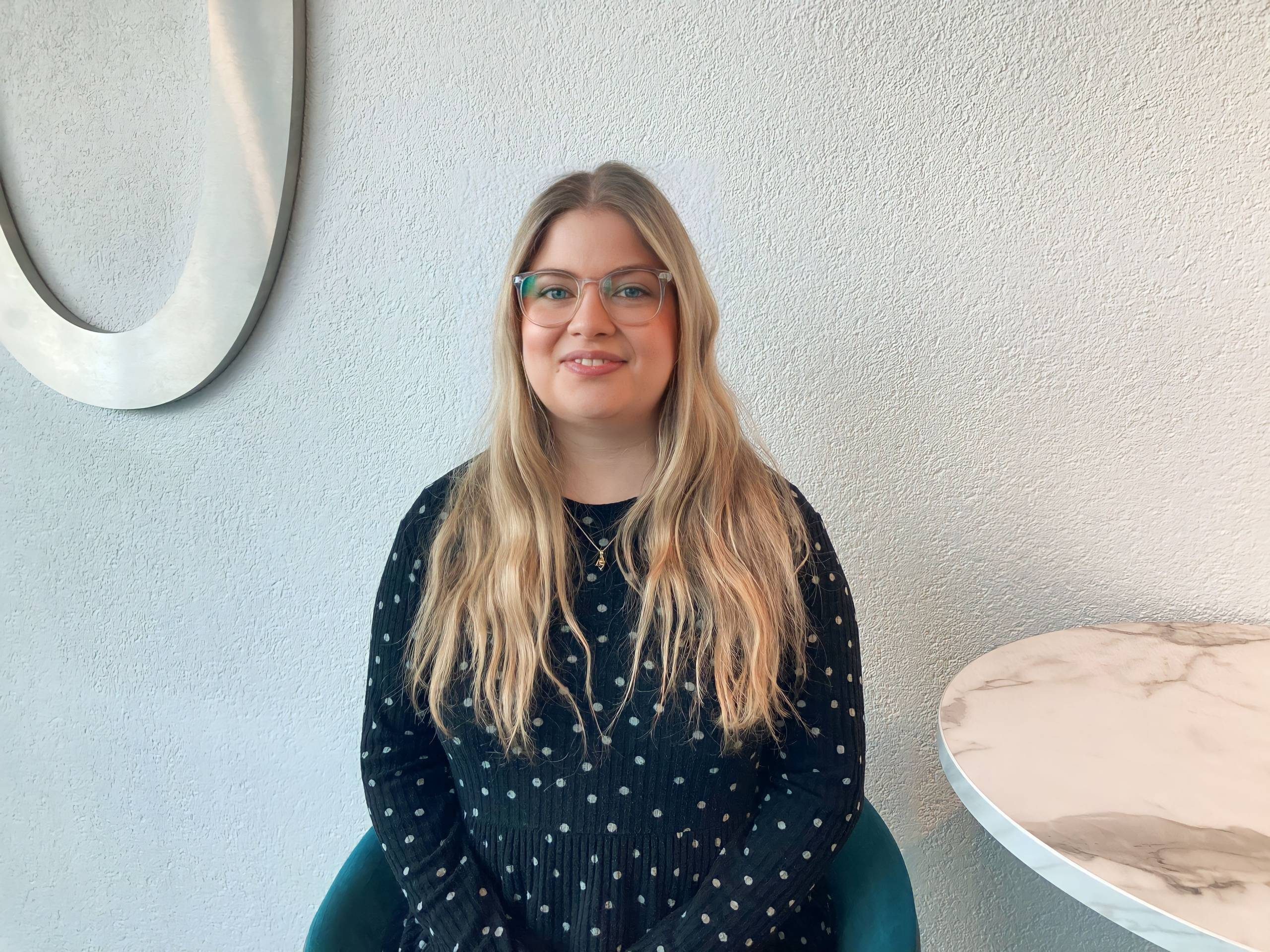 person in a blue dress with long hair and glasses
