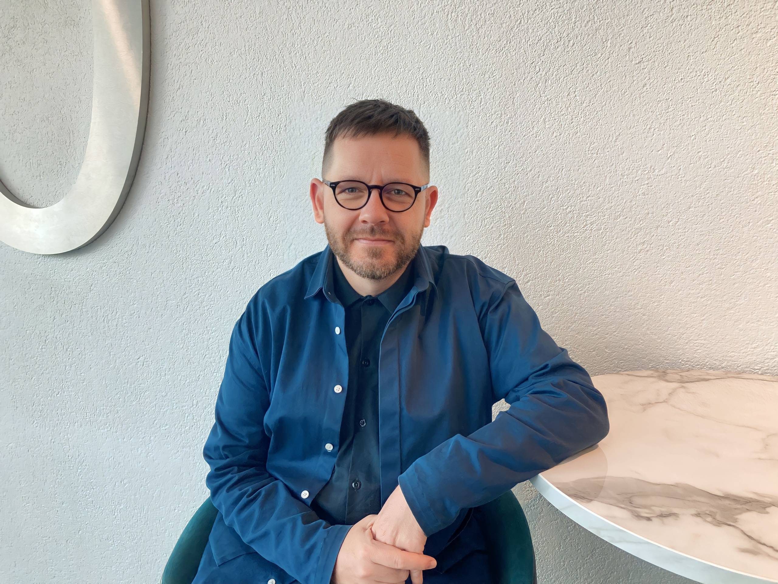 person in glasses and a denim shirt sitting