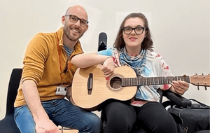 person in mustar top with a person holding a guitar