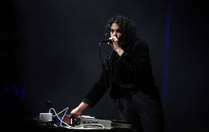Performer with technology in a black jacket and mic in their hand