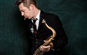 person in a suit with a saxophone in front of a green background