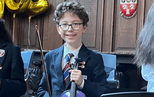 a boy in a blazer holding a violin