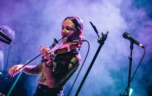 Frankie Archer under purple lights playing the violin.