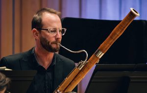 Lawrence wearing glasses playing the basson.