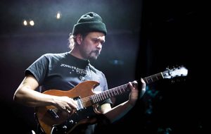 The Early Purple in a black hat playing his guitar.