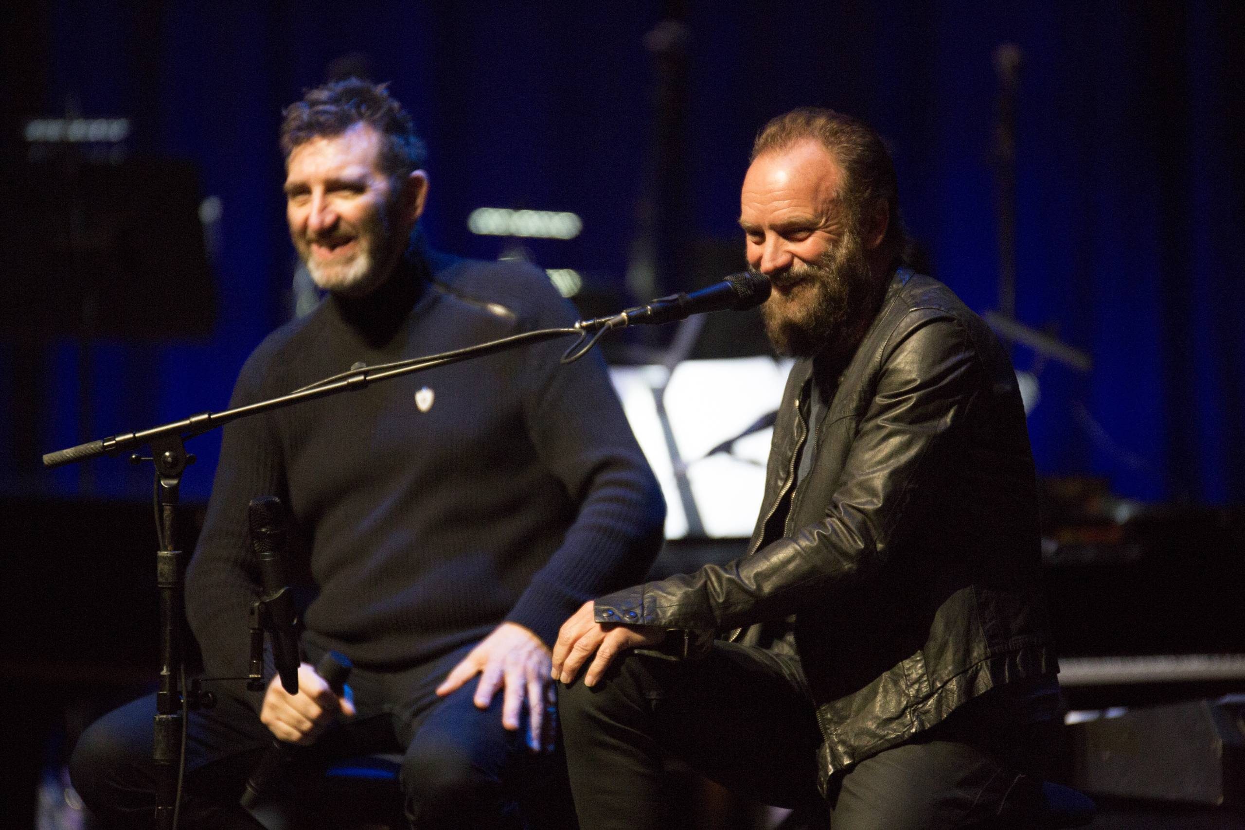 Sting and Jimmy Nail wearing black and laughing.