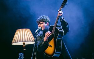 Finn Forster playing his guitar under blue light