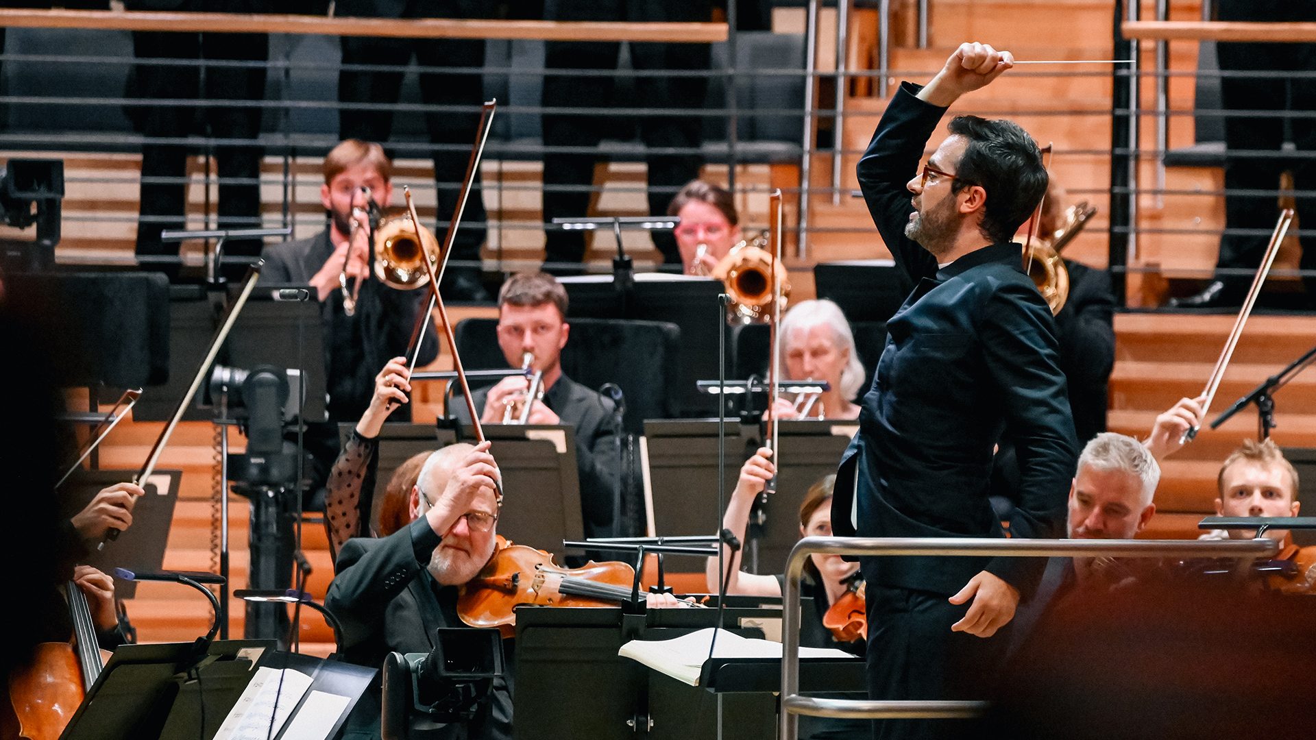 Conductor Dinis Sousa energetically leads Royal Northern Sinfonia, with musicians playing instruments on stage.