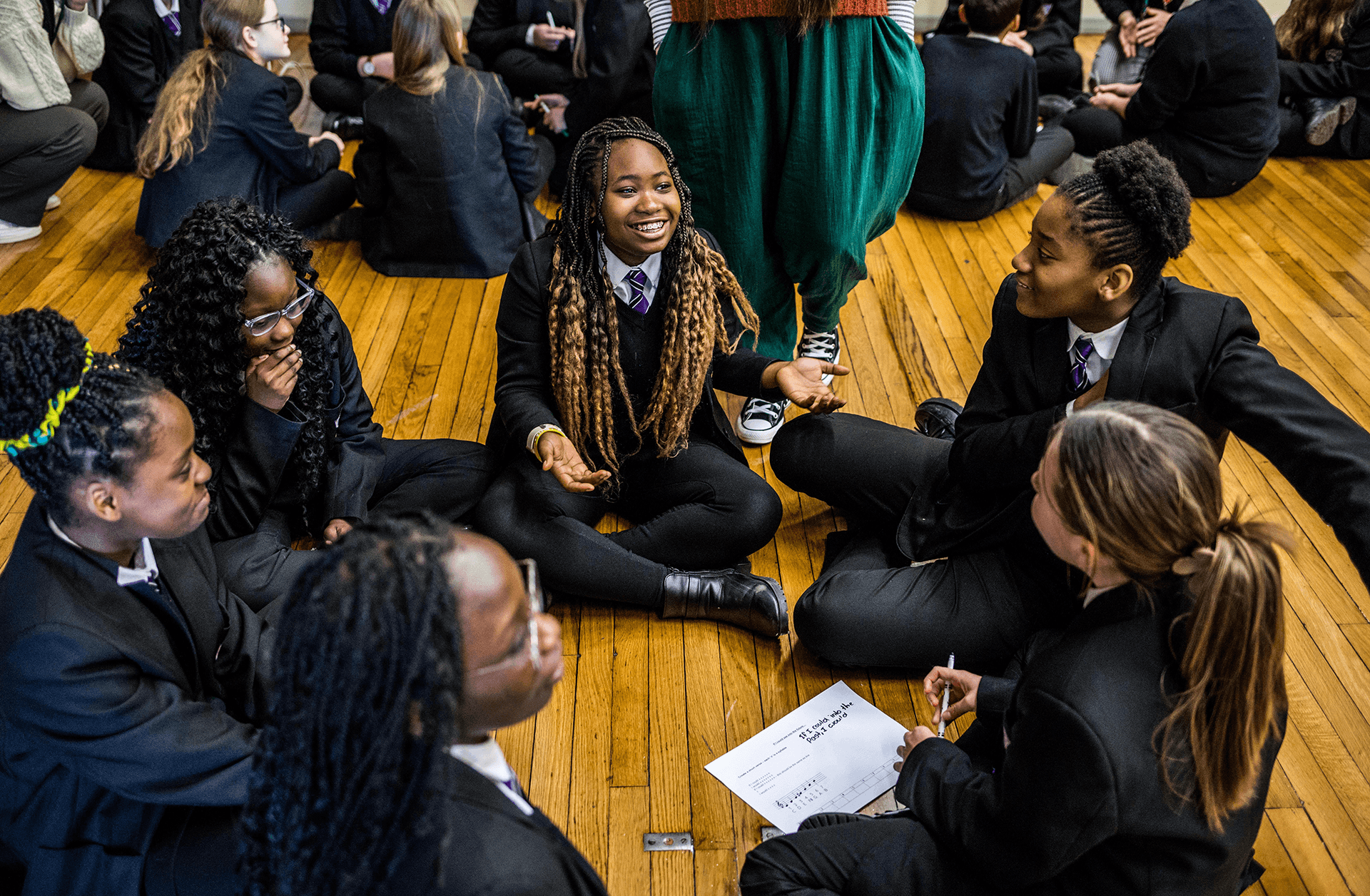 A group of girls it in a circle discussing songwriting