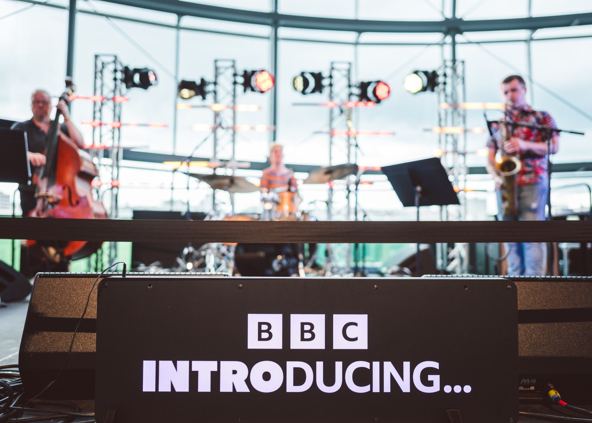 A jazz trio performs on stage behind a sign that reads BBC Introducing...