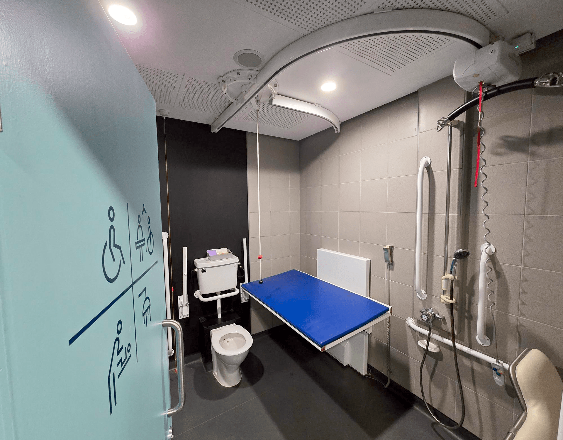 An accessible toilet showing a hoist, changing table and shower.
