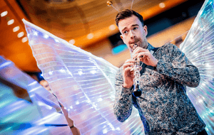Michael O'Donnell playing his oboe in a patterned shirt and fairy wings.