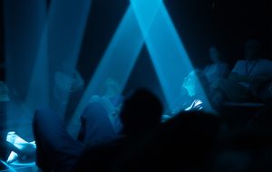 Audience members illuminated by beams of light.
