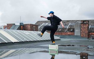 Dancer performing outdoors on a wet industrial rooftop.