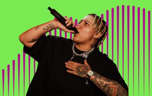 Performer singing into a microphone against a bright green and pink graphic background.