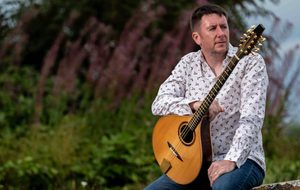 Daoirí Farrell seated outdoors holding a bouzouki.