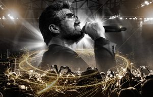 Singer performing into a microphone above a crowd, with light effects.