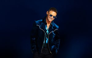 Marti Pellow: A man with short brown hair wearing sunglasses, a blue velvet jacket, a blue and black shirt and pinstripe trousers.