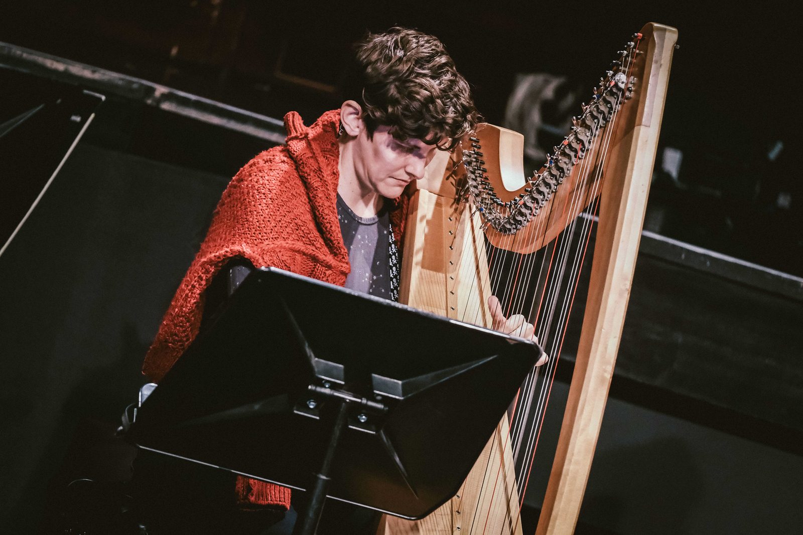 Steph West playing the harp on stage.