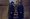 Two brothers stand side by side with a staircase behind them.