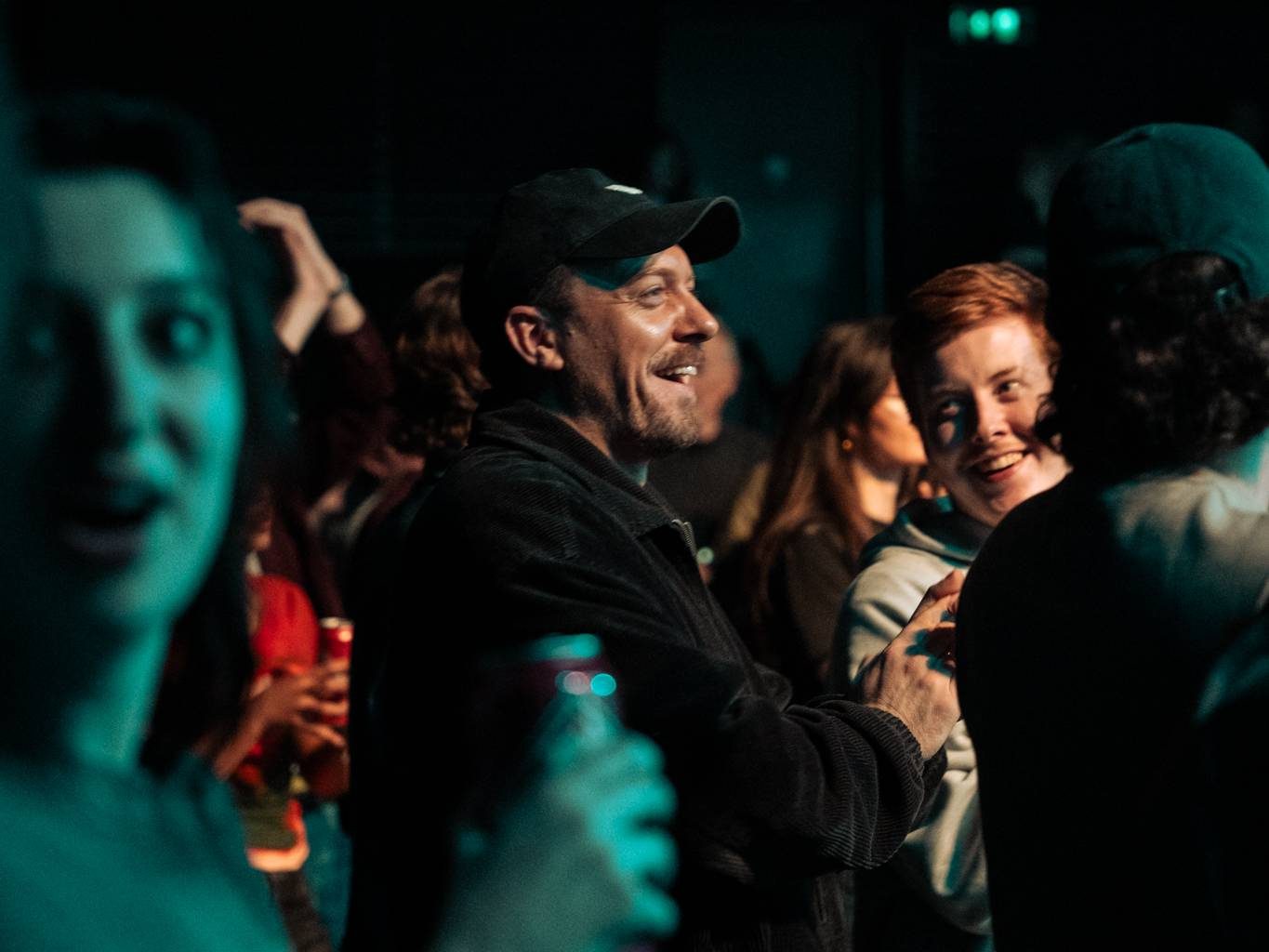 People smiling and chatting at a gig