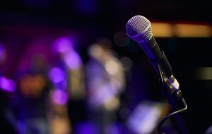 Microphone on stage, with a blurred purple lit background